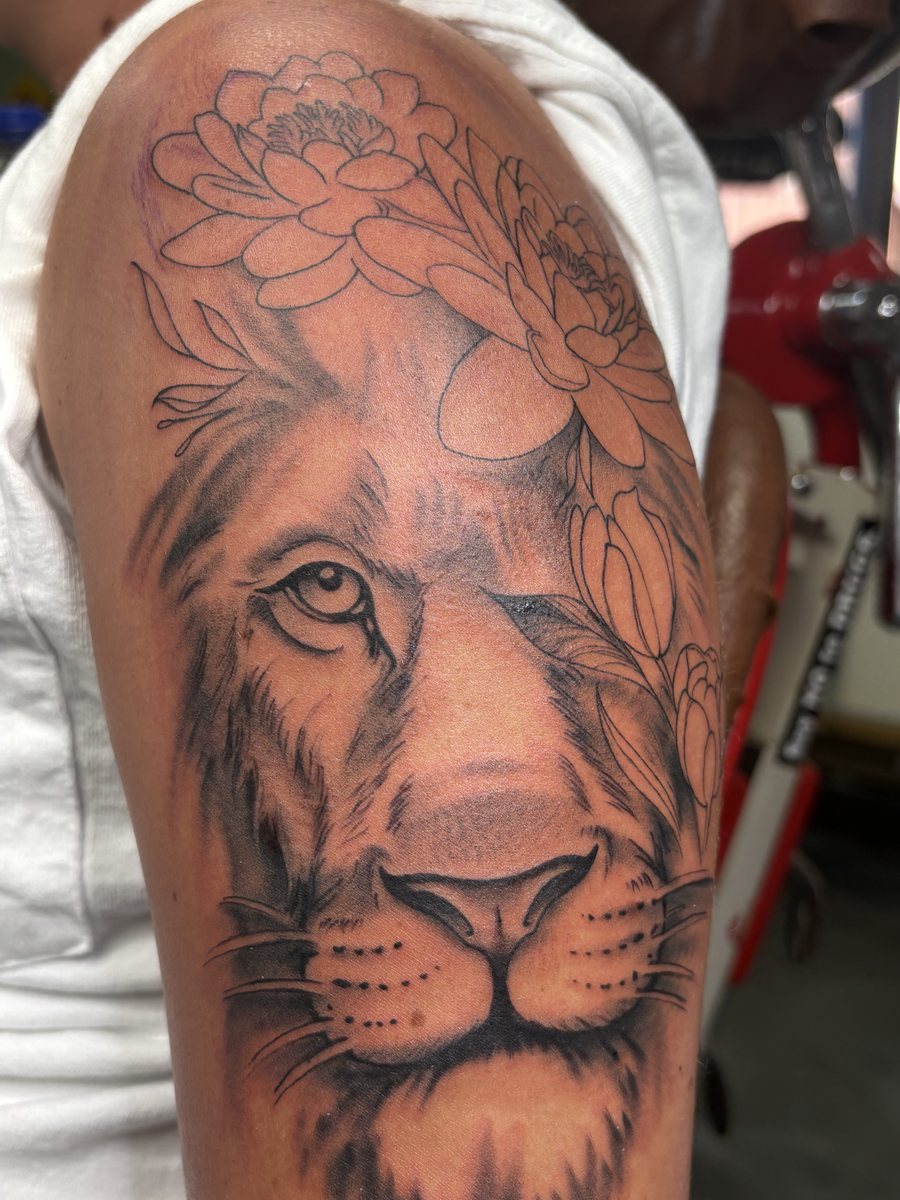 Black and grey lion and flowers tattoo on the shoulder