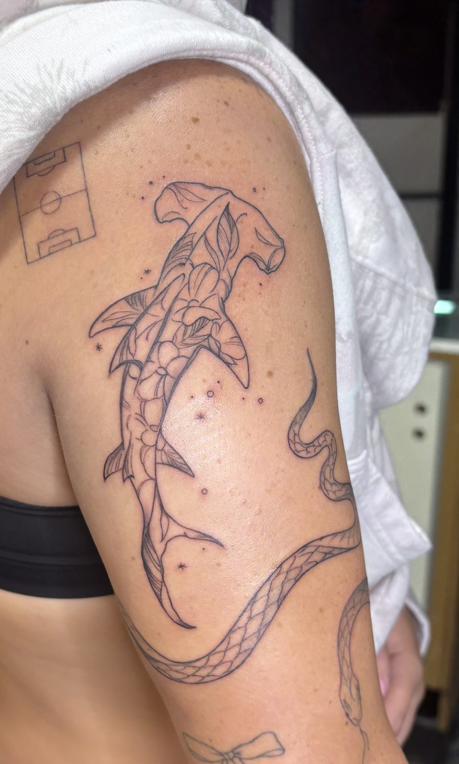 Fine-line hammerhead shark tattoo with floral fill, shoulder